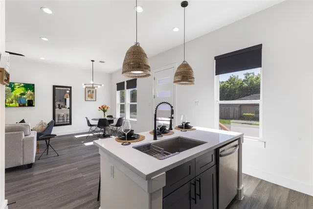 a kitchen that has a sink a stove and a table with wooden floor