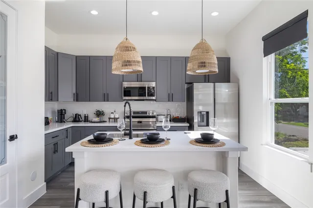 a kitchen with sink a stove and chairs with wooden floor