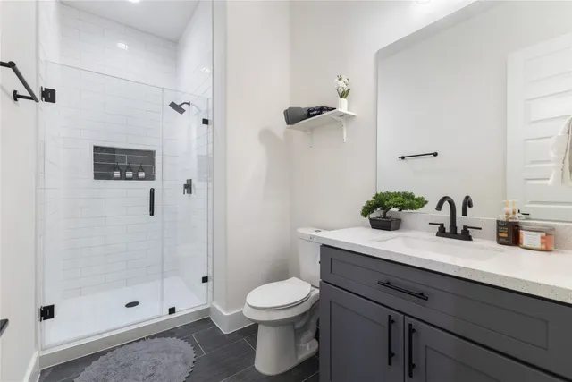 a bathroom with a granite countertop sink a toilet and shower