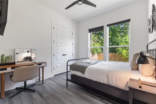 a bedroom with a bed a desk and chair with windows