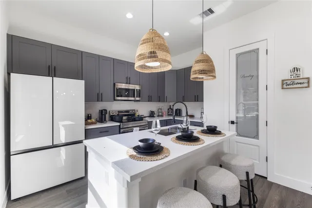 a kitchen with a refrigerator a stove a sink and chairs