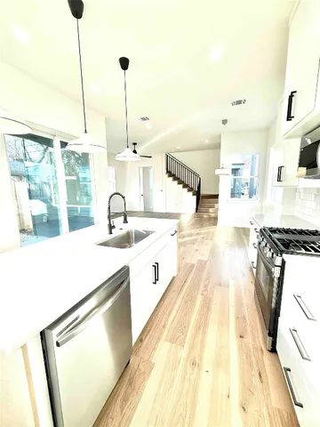 a large kitchen with kitchen island a sink a stove and a wooden floors