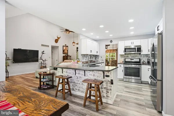 a kitchen with stainless steel appliances granite countertop a stove top oven a sink a dining table and chairs