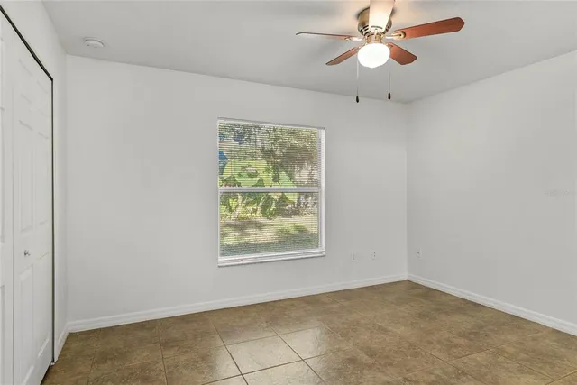 an empty room with windows and fan