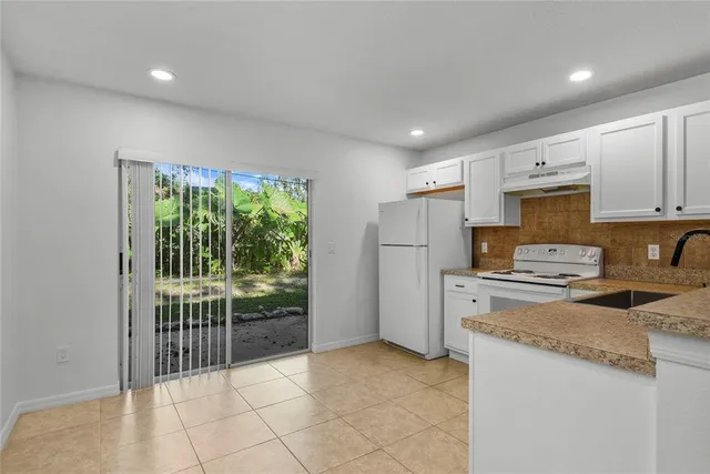 a kitchen with a refrigerator a stove top oven a sink and cabinets