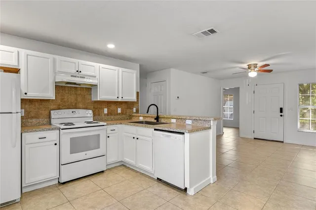 a kitchen with granite countertop white cabinets and white appliances