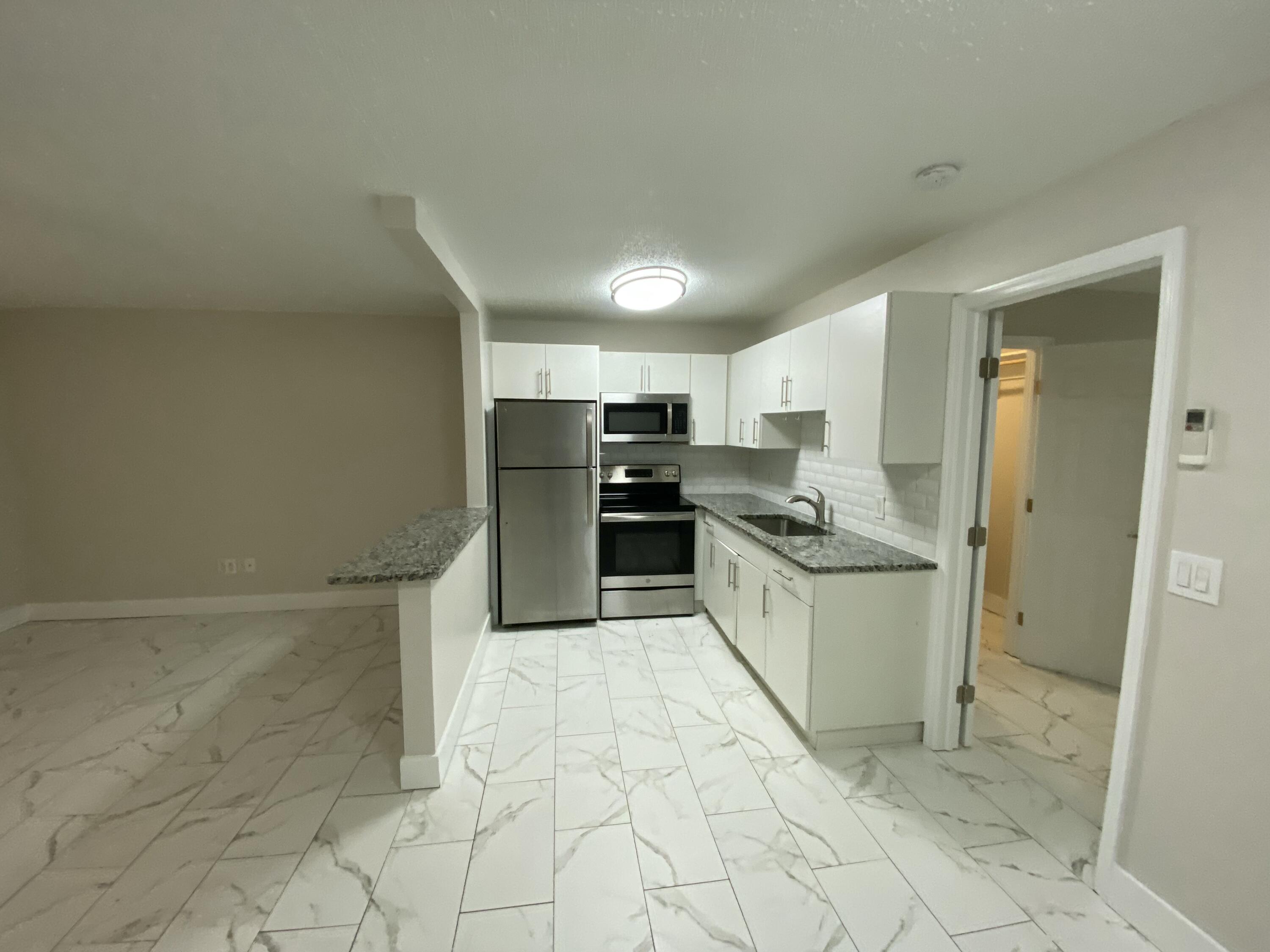 914 North Federal Highway, Unit 2 Lake Worth Beach, FL 33460 - Photo 3 of 13 a kitchen with granite countertop a refrigerator and a stove top oven