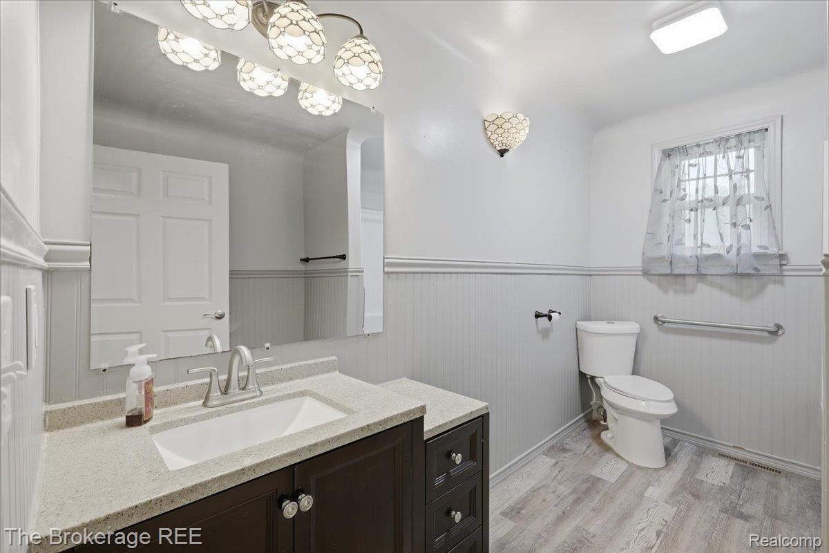 11973 East Brooks Road Lennon, MI 48449 - Photo 20 of 28 Vanity with undermount sink, wood-finish flooring, beadboard wall paneling, and wall-mounted lighting fixtures