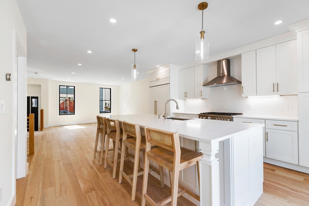 300 West 3rd Street, Unit 300 Boston, MA 02127 - Photo 8 of 23 a kitchen with stainless steel appliances kitchen island granite countertop a stove a sink a refrigerator and white cabinets with wooden floor
