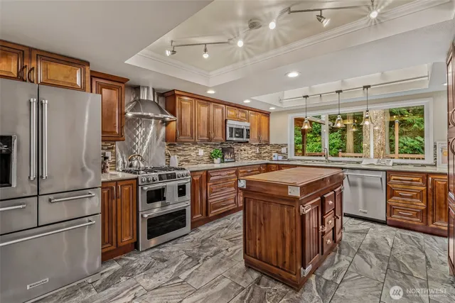 a kitchen with stainless steel appliances granite countertop a stove a refrigerator and a sink