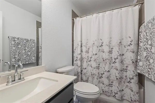 a bathroom with a shower curtain sink and a toilet