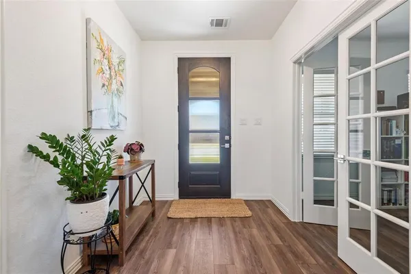 a view of a hallway with wooden floor and a potted plant