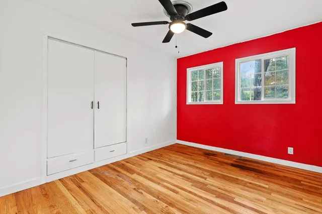 a view of empty room with wooden floor and fan