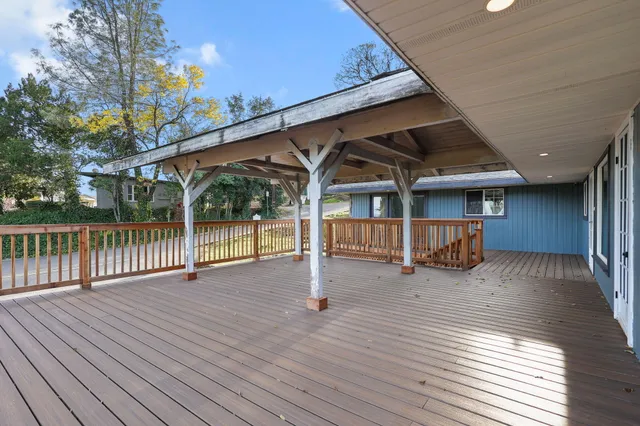 a view of a house with wooden deck and floor to ceiling window