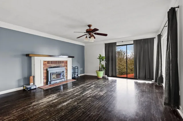 an empty room with wooden floor fireplace and a window