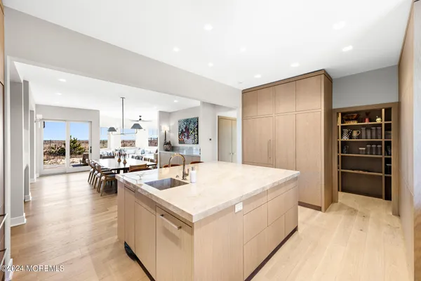 a view of a dining room and livingroom with furniture wooden floor a rug a painting and a chandelier