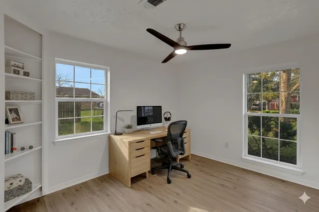 an empty room with wooden floor cabinet and windows