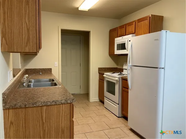 a white refrigerator freezer and a stove sitting inside of a kitchen