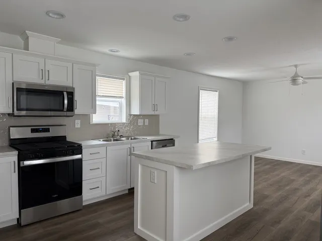 a kitchen with stainless steel appliances granite countertop a stove a sink and a microwave