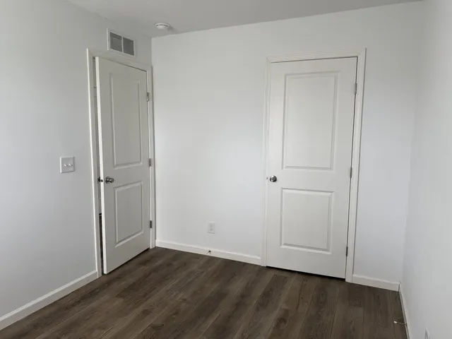 an empty room with wooden floor and closet area