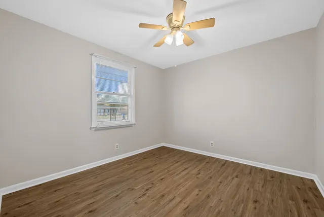 a view of an empty room with window and wooden floor