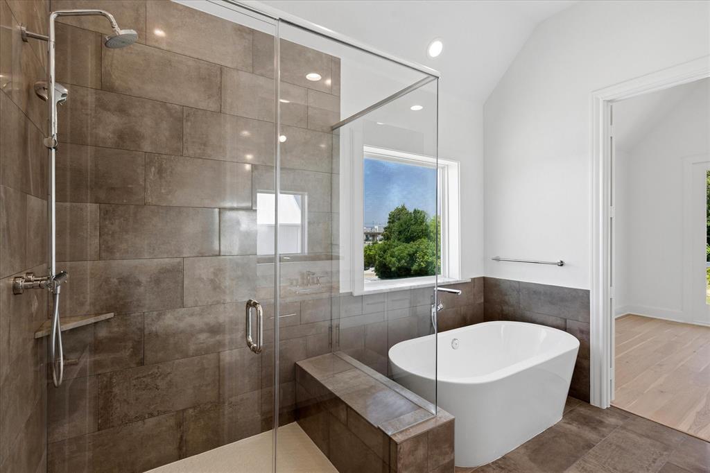 1362 East Crosby Road Carrollton, TX 75006 - Photo 13 of 22 Contemporary bathroom featuring a spacious walk-in shower with a built-in bench, a freestanding soaking tub, and large format wall and floor tiling