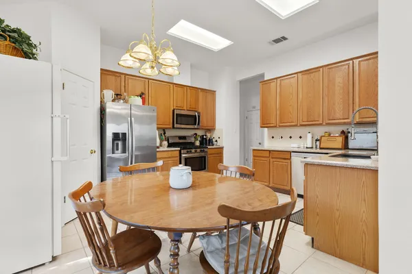 a kitchen with a dining table chairs and a refrigerator