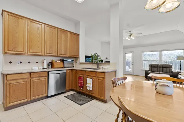 a kitchen with stainless steel appliances granite countertop a stove top oven a sink dishwasher and white cabinets with wooden floor