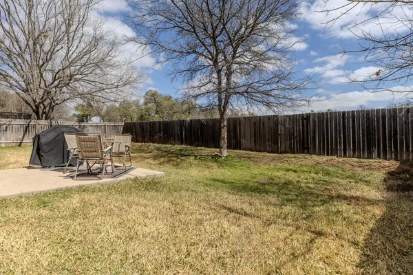 a view of backyard with table and chairs and wooden fence