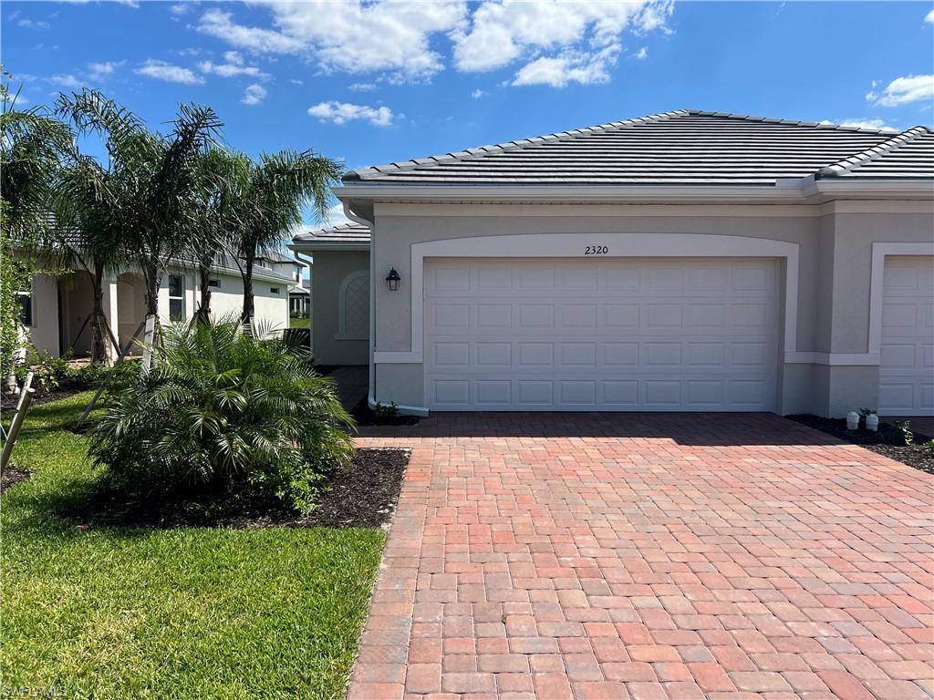 2320 Dragonfruit Way Naples, FL 34120 - Photo 1 of 33 View of front facade with stucco siding, a tiled roof, decorative driveway, and an attached garage