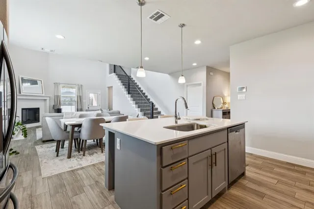 a kitchen with a sink a counter space appliances and a living room view