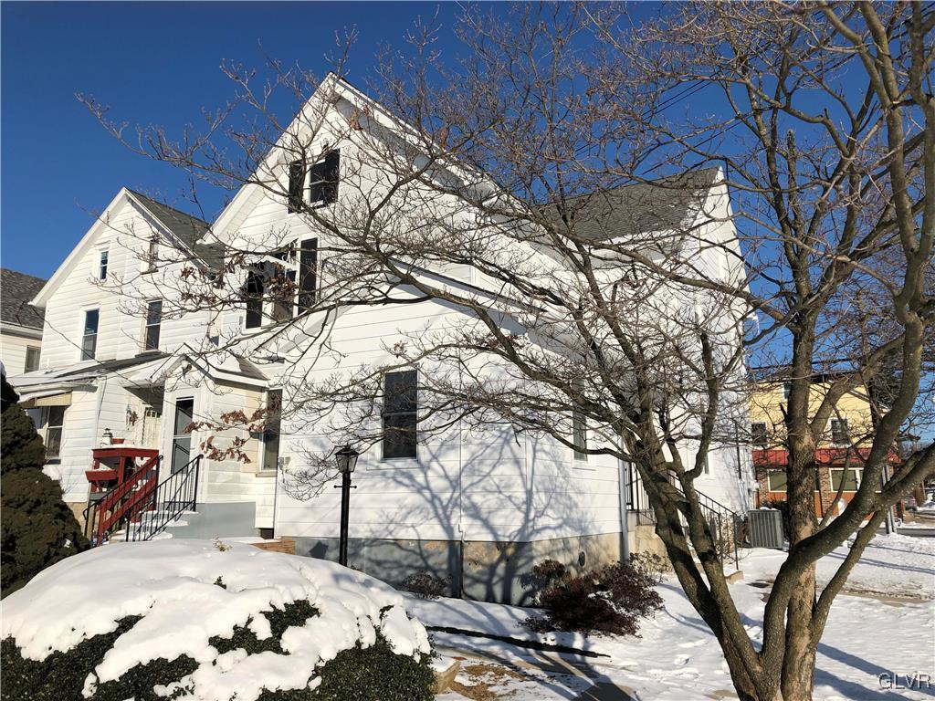 a view of a white house with a snow in the yard