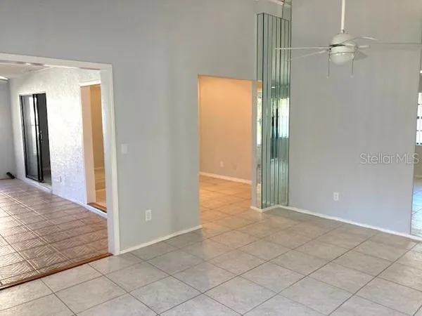 en empty room with windows and chandelier fan