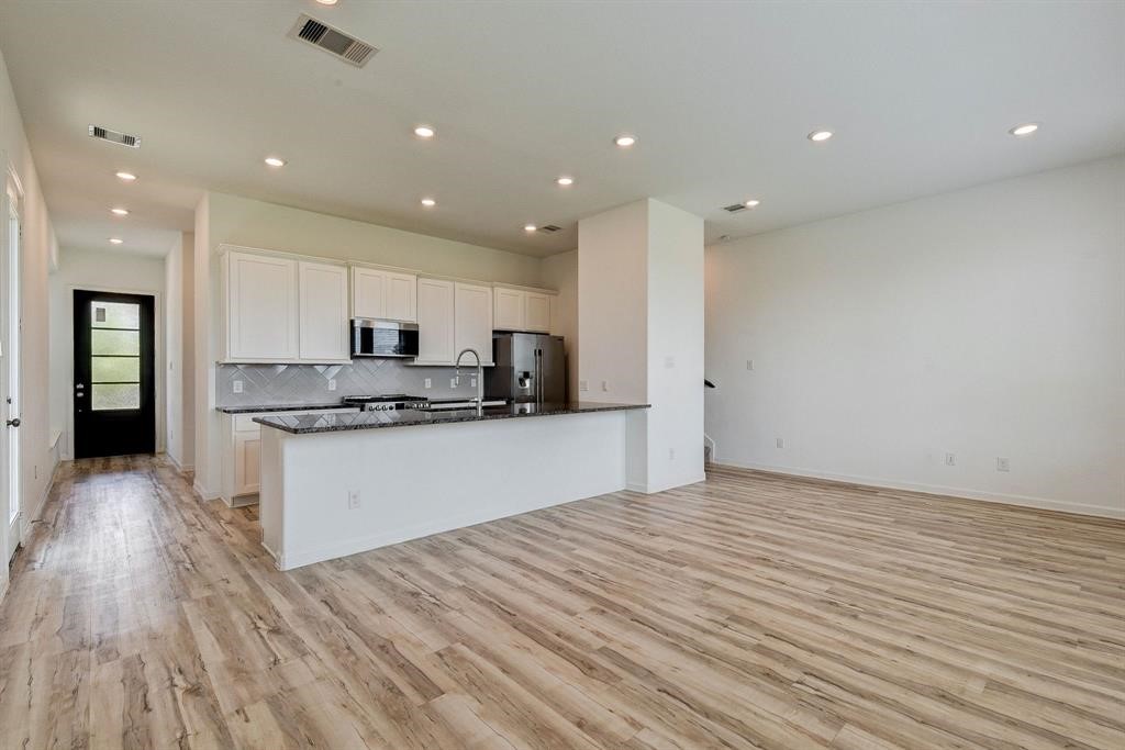 4115 Balboa Drive Iowa Colony, TX 77583 - Photo 2 of 9 a large white kitchen with kitchen island a sink dishwasher a refrigerator and white cabinets with wooden floor