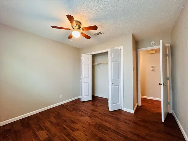 an empty room with wooden floor closet and fan