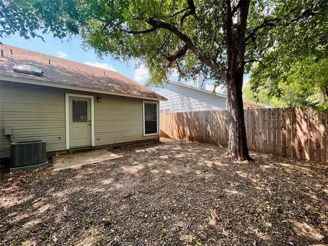 a view of a house with a large tree and wooden fence