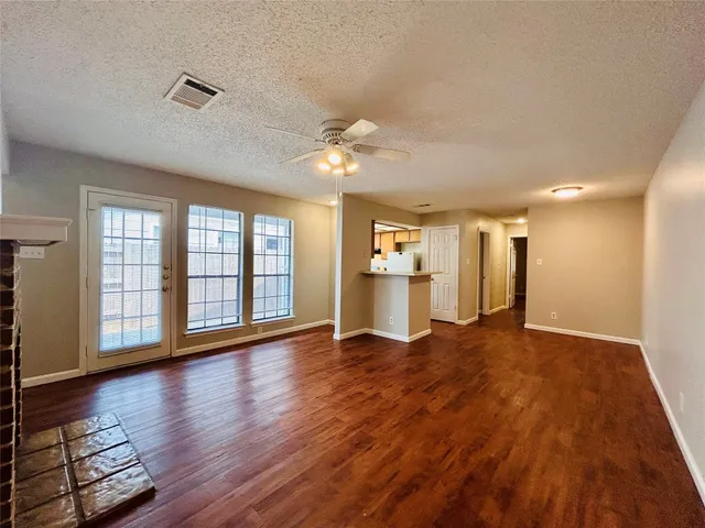 a view of an empty room with window and wooden floor