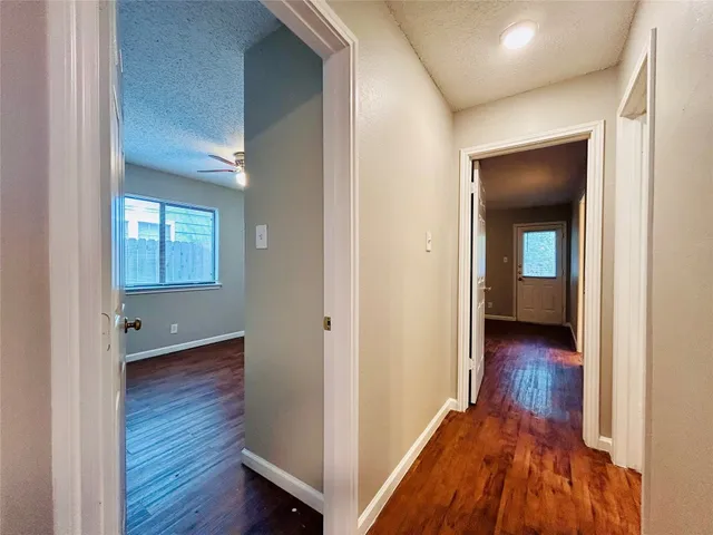 a view of a hallway with wooden floor and a bathroom