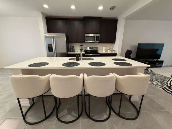 a dining room with furniture a rug and kitchen view