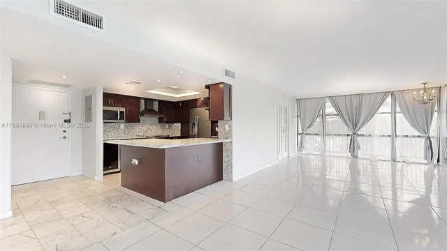a kitchen with stainless steel appliances kitchen island granite countertop a refrigerator and a sink