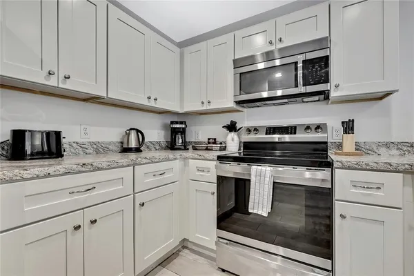 a kitchen with granite countertop white cabinets stainless steel appliances and a sink