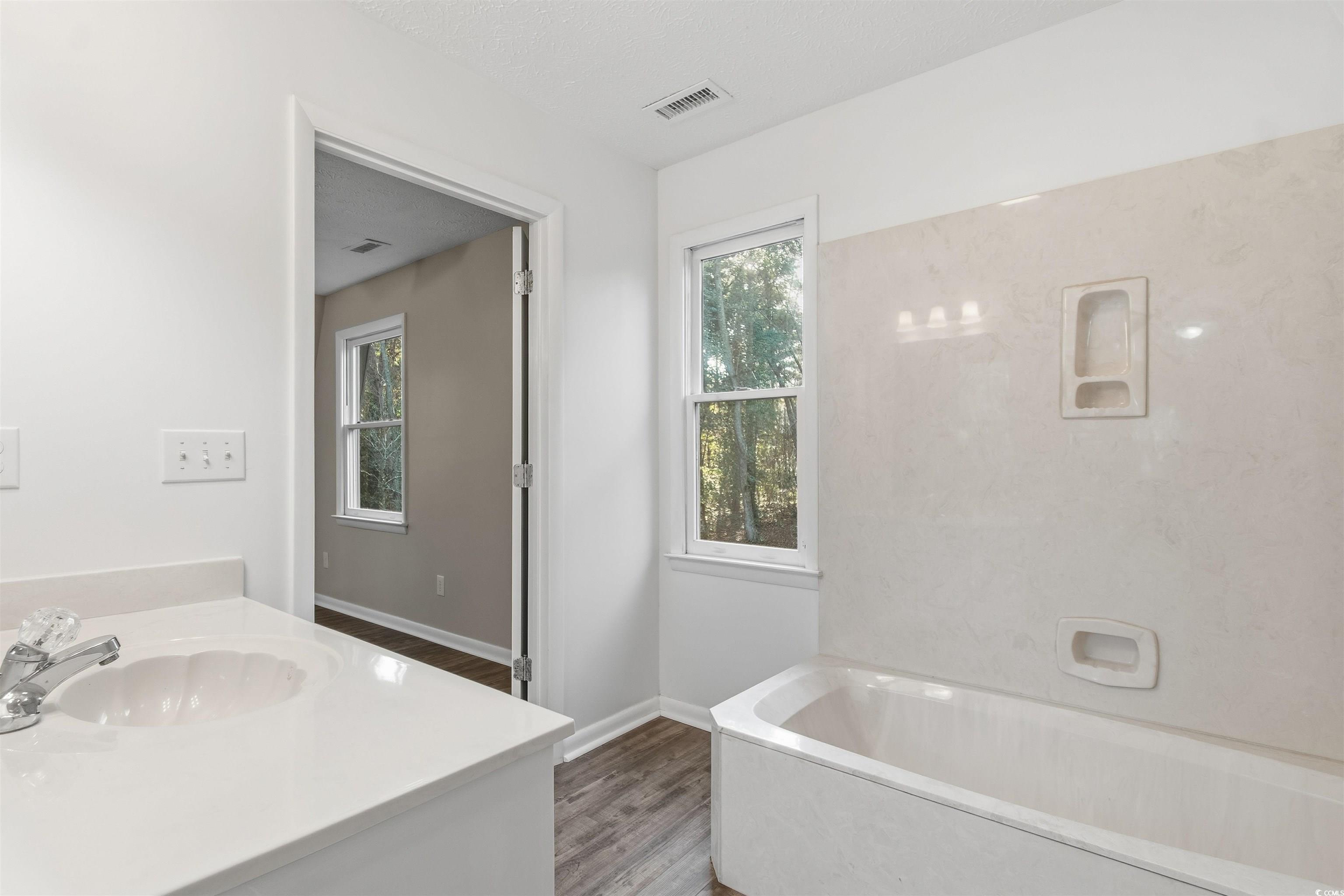 50 Irvin Enzor Road North Fair Bluff, NC 28439 - Photo 20 of 26 upstairs Full bathroom featuring vanity, a garden tub, LVP floors, and a textured ceiling
