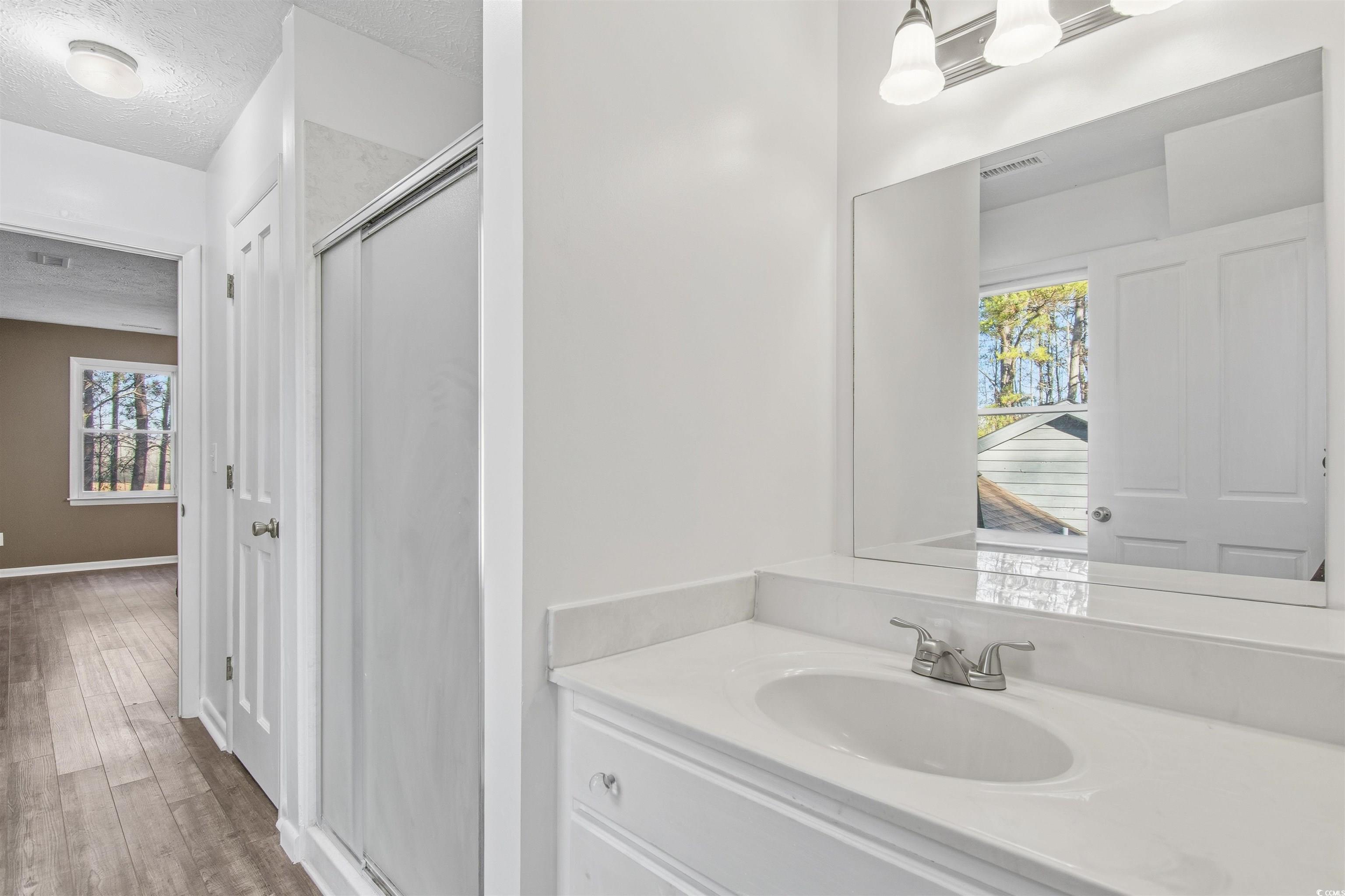 50 Irvin Enzor Road North Fair Bluff, NC 28439 - Photo 21 of 26 upstairs Bathroom with a stall shower, vanity, a textured ceiling, and LVP floors