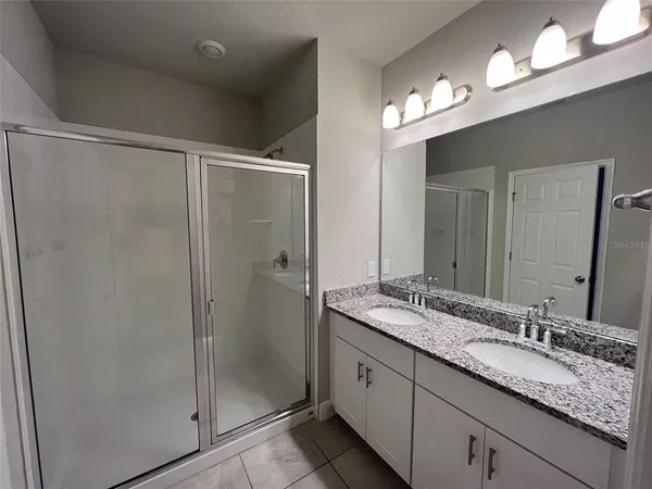 a bathroom with a granite countertop sink a shower and a mirror
