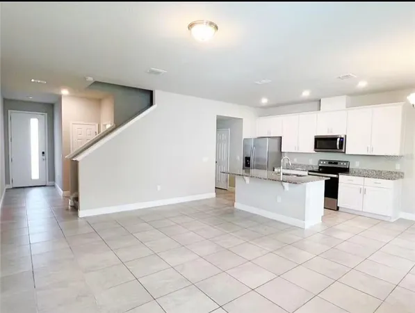 a view of kitchen with stainless steel appliances kitchen island granite countertop a refrigerator and a stove top oven
