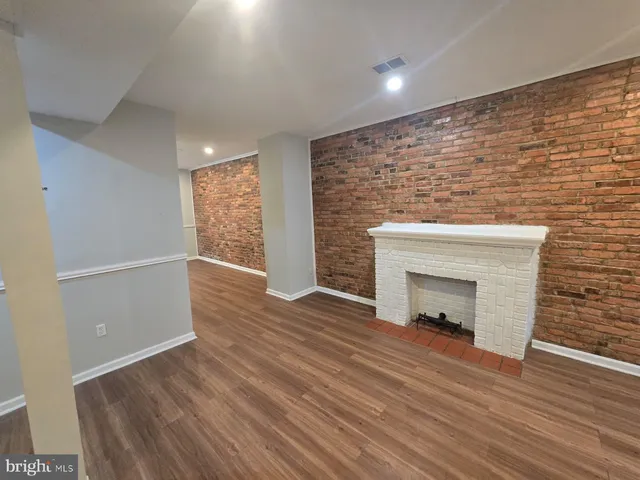 an empty room with wooden floor fireplace and windows