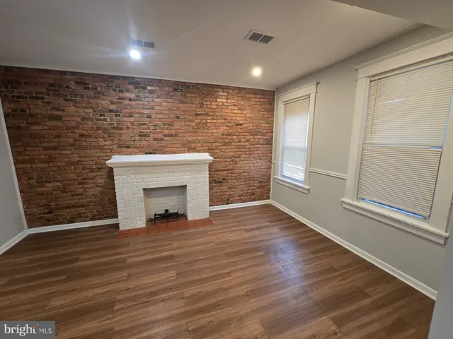 a view of a livingroom with wooden floor and a fireplace