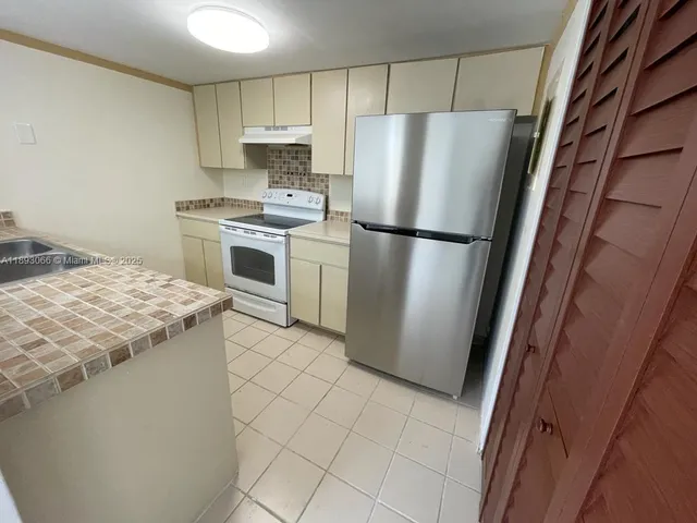 a kitchen with a refrigerator sink and cabinets