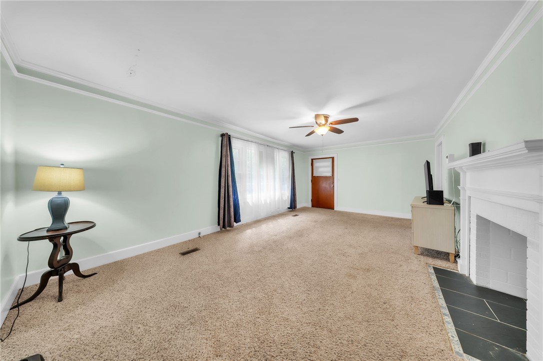An inviting fireplace with a classic mantel anchors this comfortable, carpeted living area.
