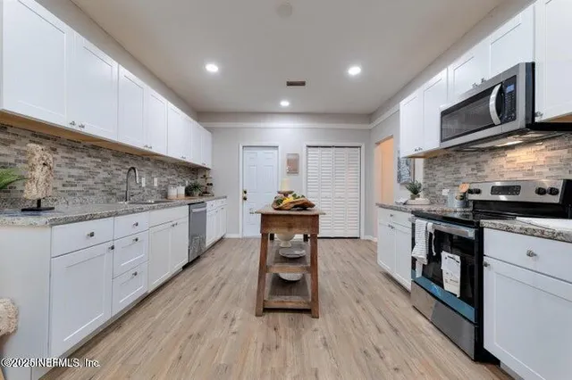 a kitchen with stainless steel appliances kitchen island granite countertop a stove a sink and a microwave